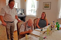 Herr Schabacker aus Lomnitz trägt sich an seinem 100. Geburtstag in das "Goldene Buch" der Gemeinde Wachau ein.